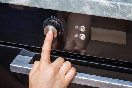 hand turning on an oven 