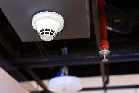 Smoke detector and fire sprinkler on the ceiling.