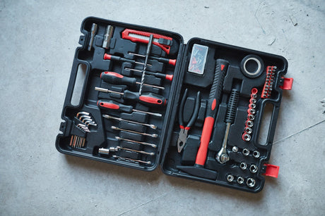 Open tool box with red hammer and screwdriver on concrete floor at construction site