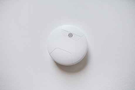 Smoke alarm sensor or detector on white ceiling