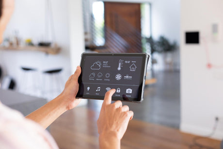 man at home using tablet with smart home interface on screen