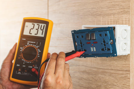 Using a digital meter to measure the voltage at an electric outlet socket box