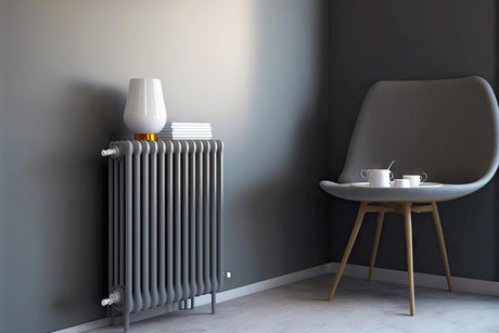 Grey heating radiator located on grey wall near small table