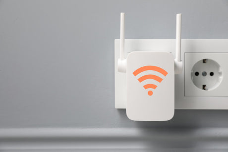 New modern repeater with WiFi symbol plugged into socket on light grey wall